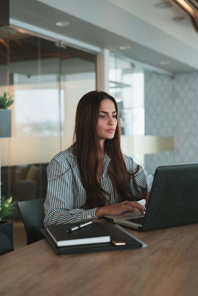 Portrait Of Brown Haired Woman Working On Laptop In Office