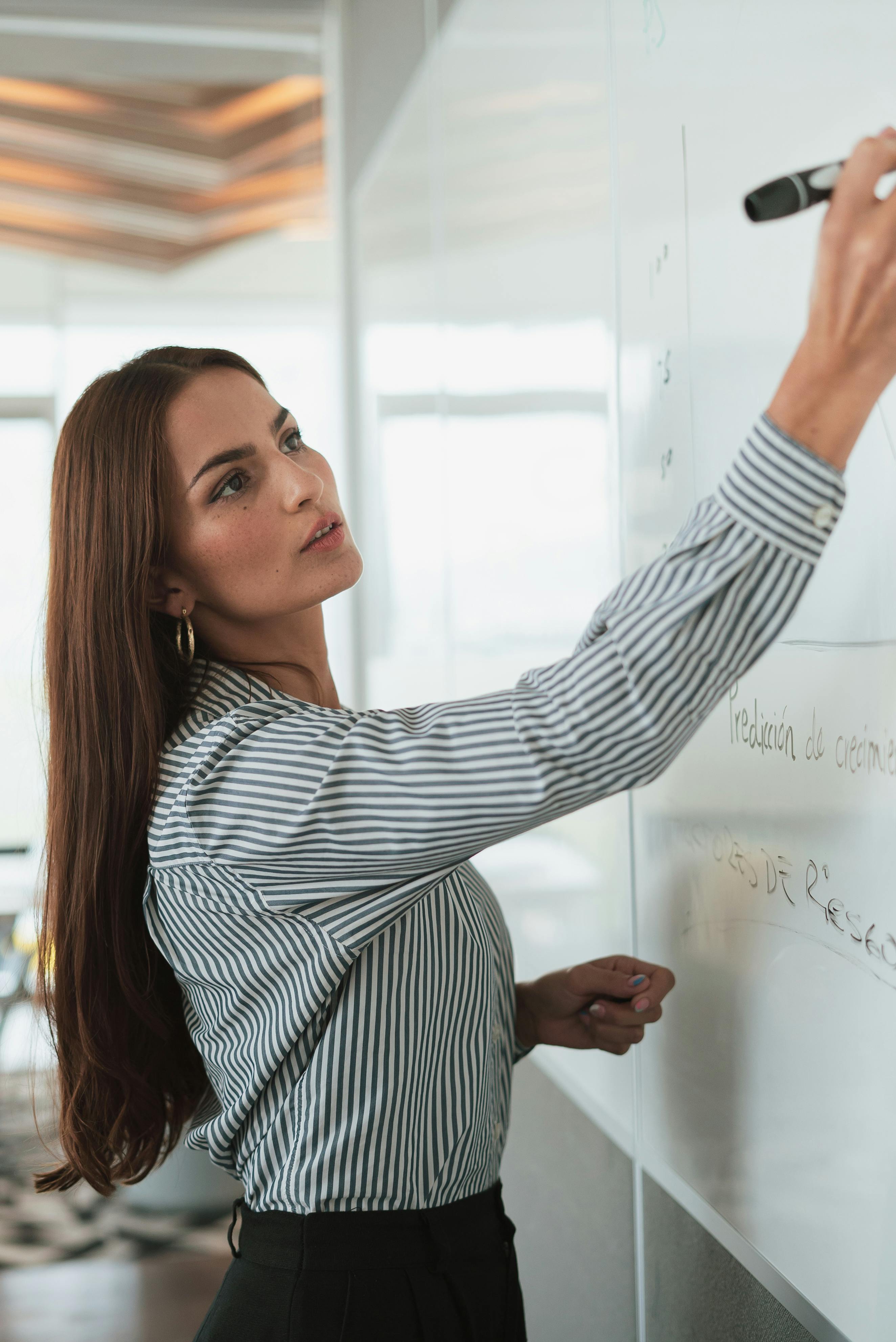 portrait of woman in shirt drawing on whiteboard in office