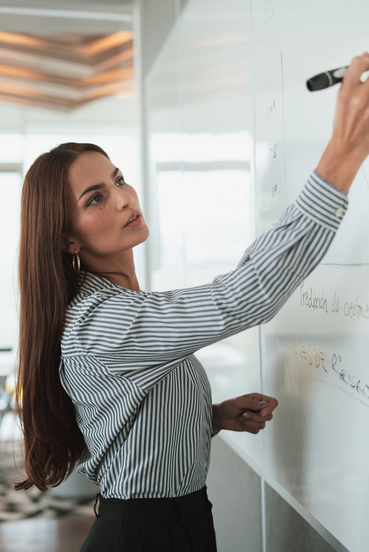 Portrait Of Woman In Shirt Drawing On Whiteboard In Office