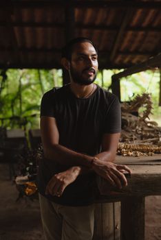 A man stands beside a reptile skeleton in a rustic, dimly-lit environment.