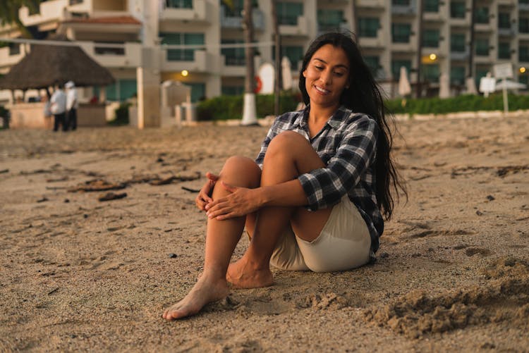 A Female Sitting On A Beach During Sunset 