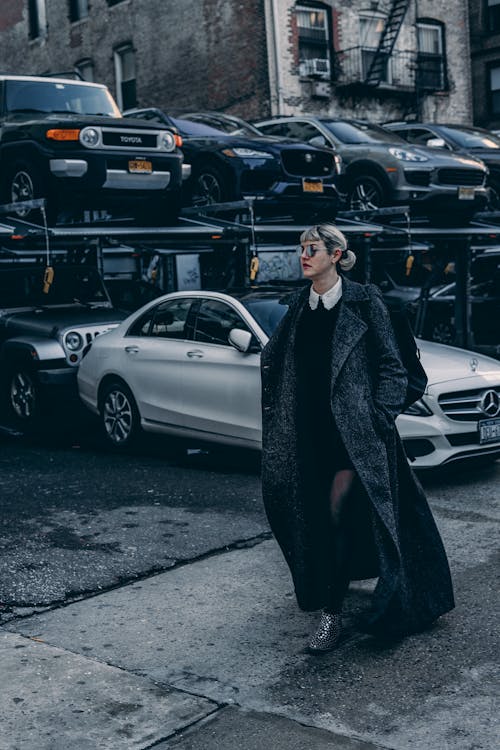 Woman Wearing a Coat Walking Beside Parked Cars