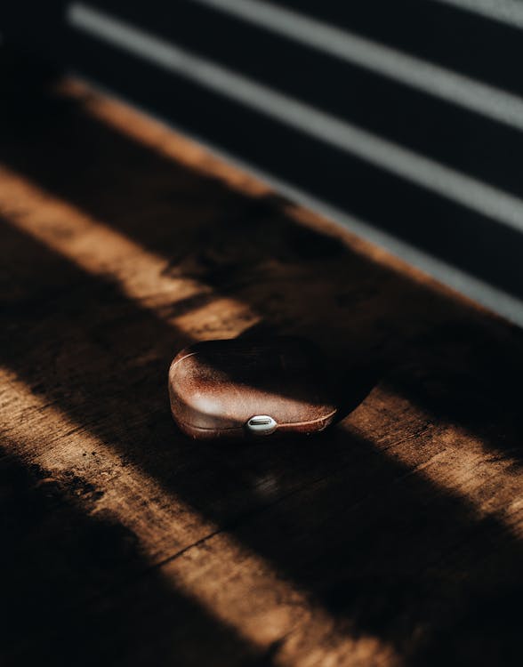 A Brown Airpod Case on a Wooden Surface Wooden Surface 