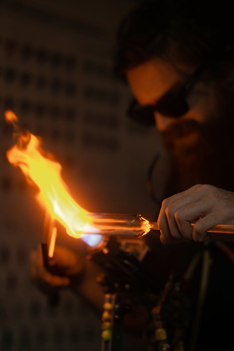 A Man Melting A Glass Tube With A Torch