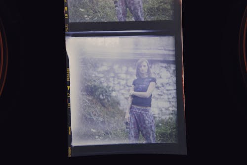 A Polaroid Picture of a Woman Standing Near Green Grass