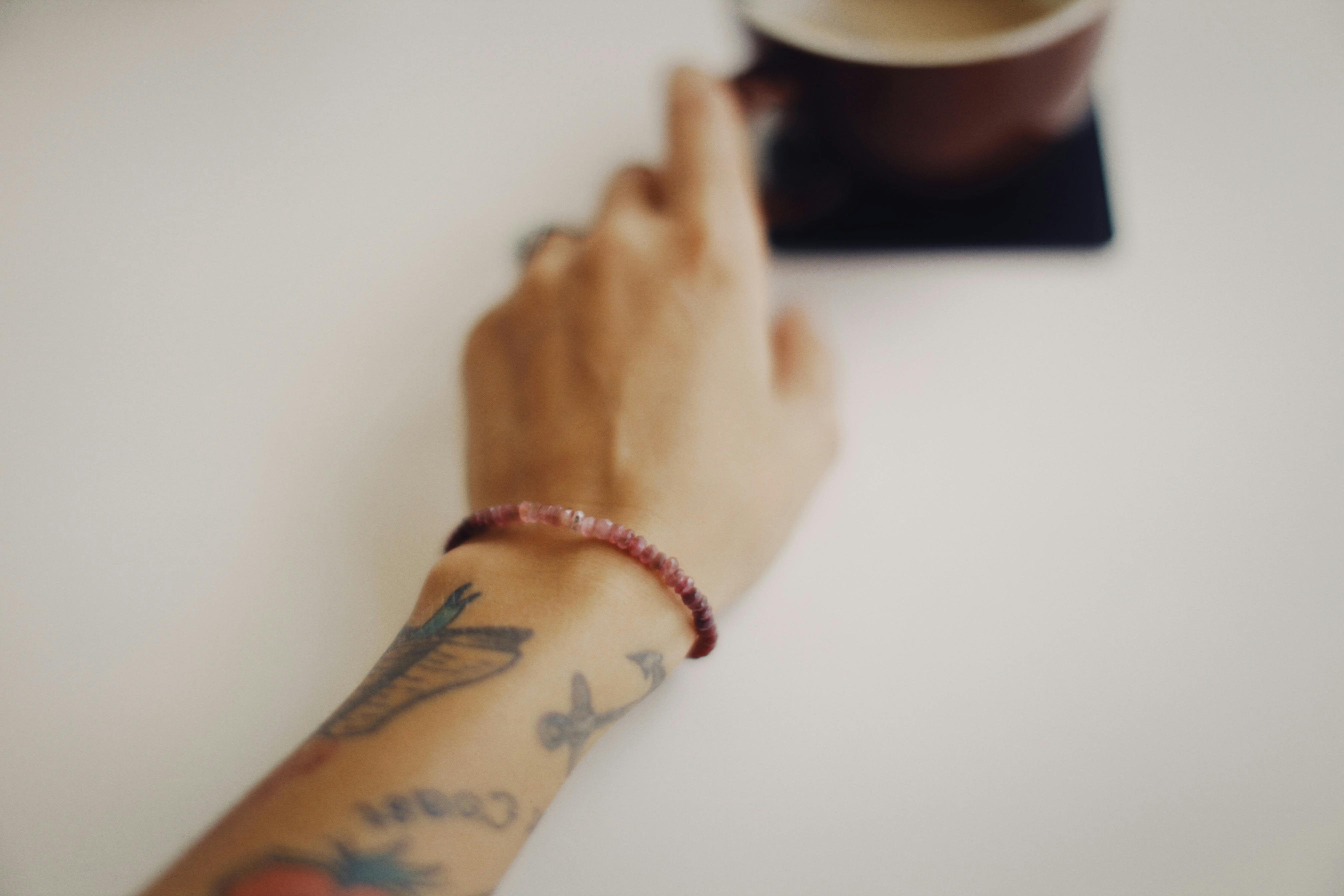 Close-Up Photo of an Arm with Tattoo and Beads Bracelet · Free Stock Photo
