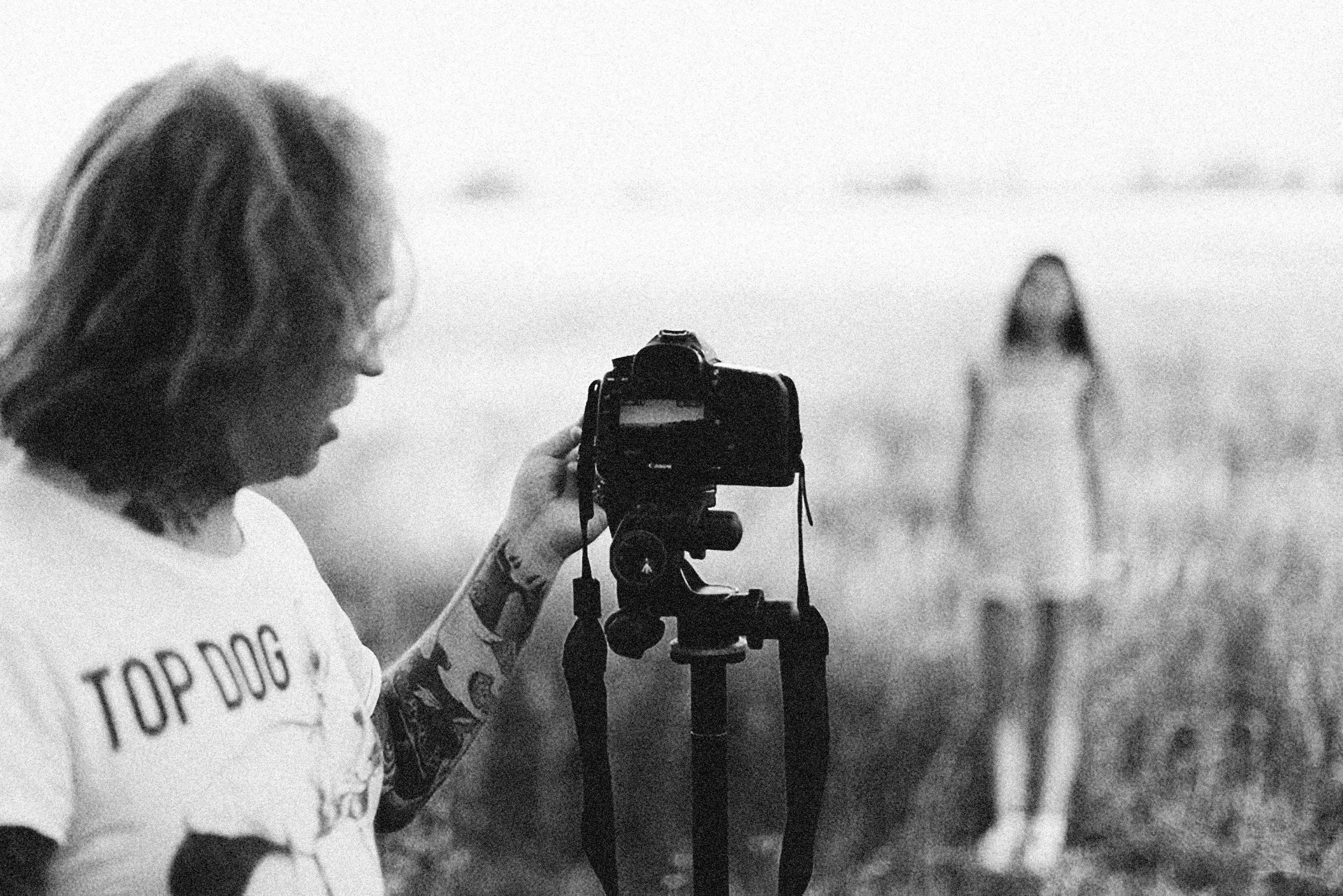 grayscale photo of a person holding a camera while taking photo of a woman