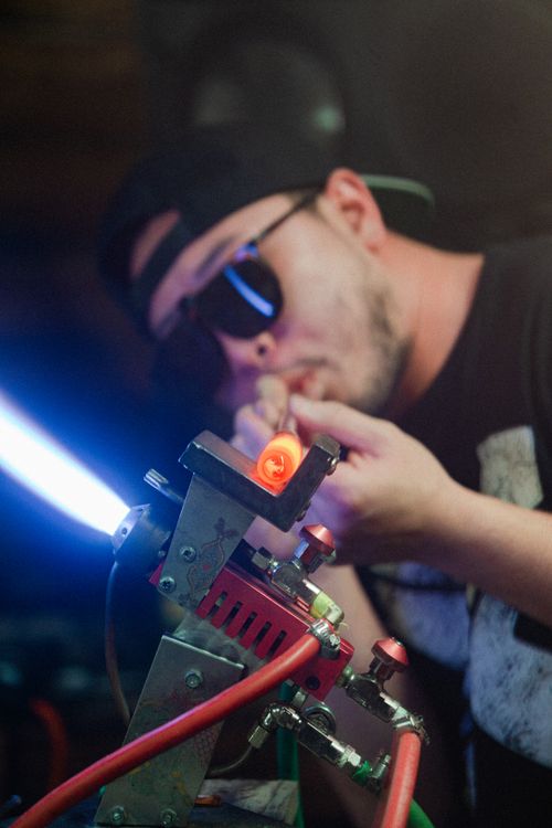 Free A man in sunglasses focusing on a laser device, highlighting technology and creativity. Stock Photo