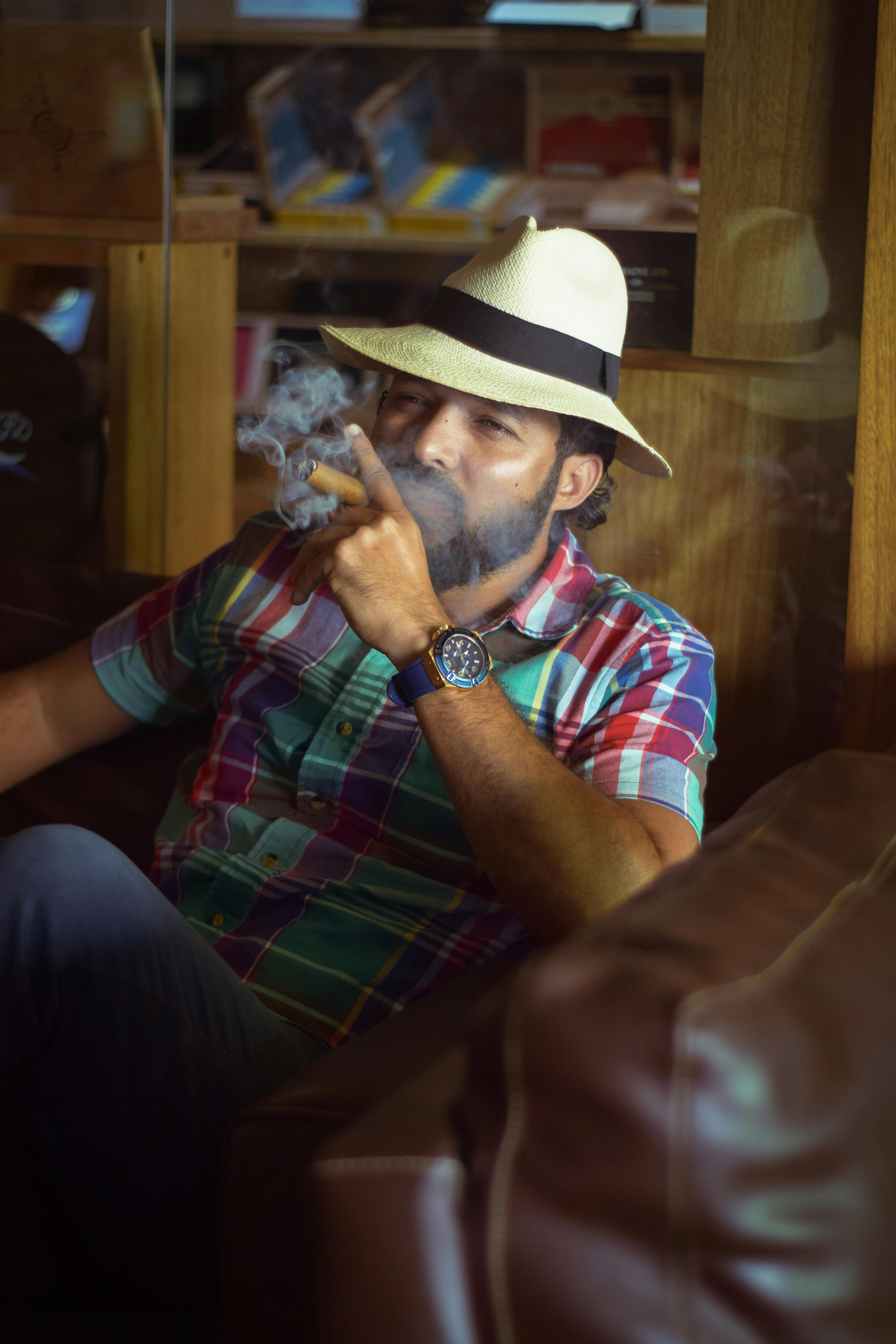 Casual man with fedora hat enjoying a cigar indoors, Puerto Plata.