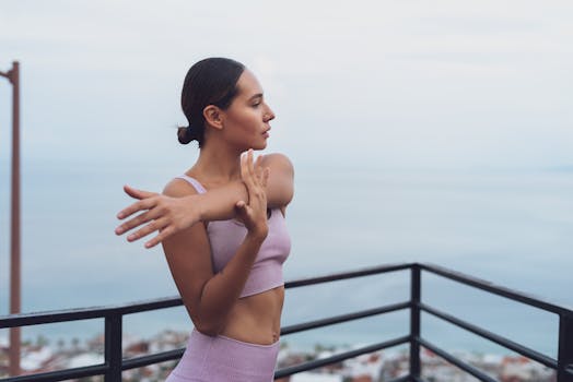 A young woman in workout attire stretching on a balcony with a sea view.