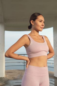 Smiling woman in sports attire enjoying a peaceful outdoor moment during the day.