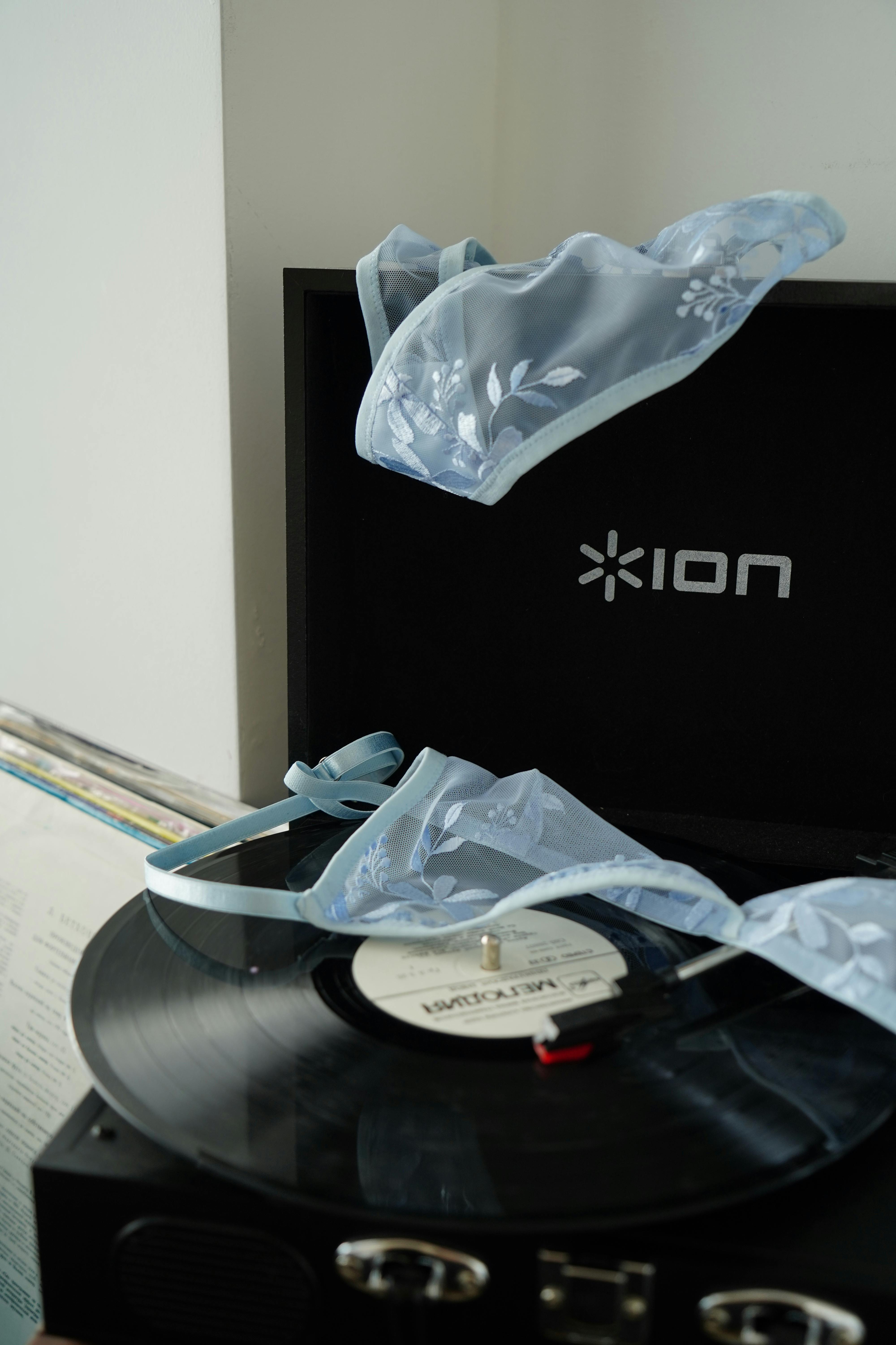 A delicate blue lingerie piece rests on a vintage turntable, adding a touch of elegance to the scene.