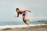 一名穿着运动服的女子在阳光明媚的海滩上跑步，展示了健康和决心