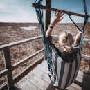 一名女子躺在吊床上，俯瞰拉脱维亚湿地的壮丽景色，享受着宁静的时刻