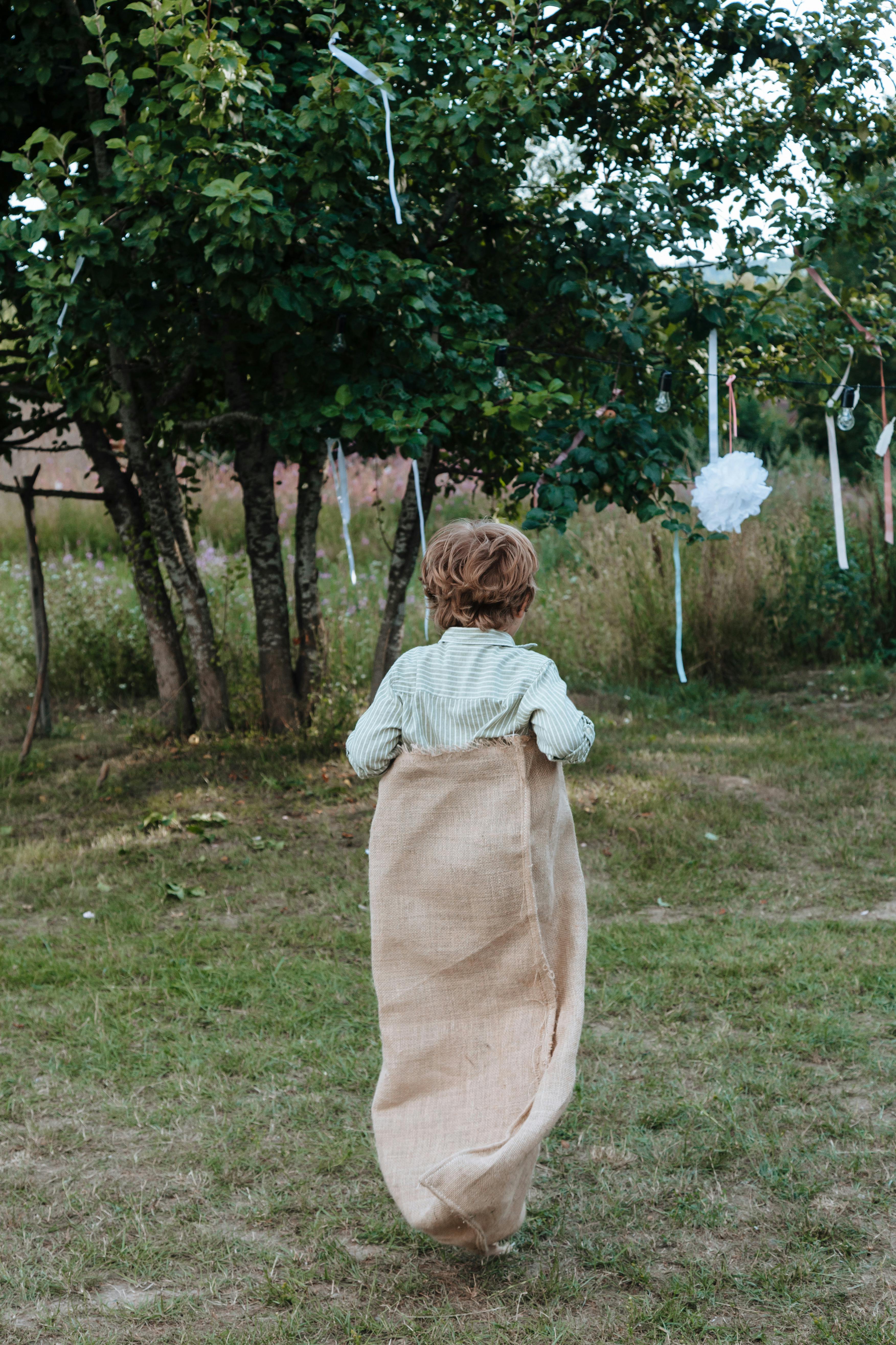 Two Children Playing Sack Race Outside the House · Free Stock Photo