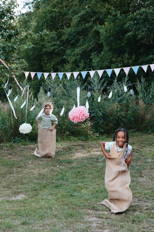 Free Girl and Boy Taking Part in Sack Race Stock Photo