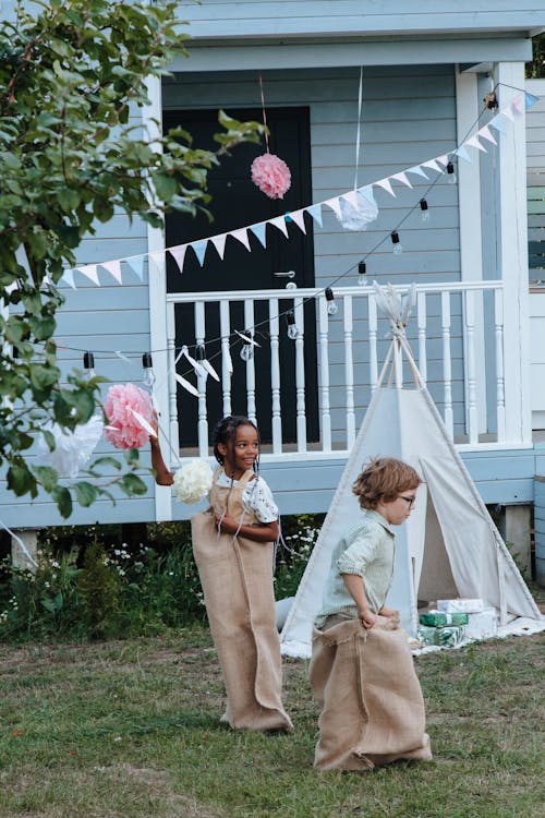 Two Children Playing Sack Race Outside the House