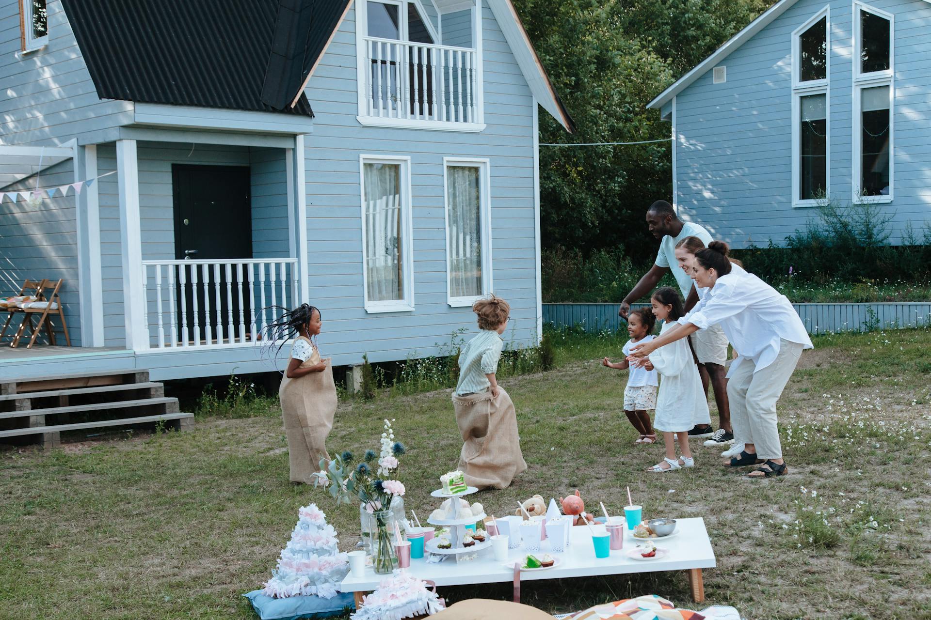 Children Playing Sack Race Outside the House with Their Family