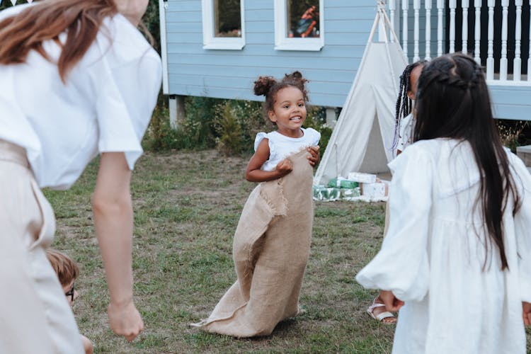 Selective Focus Of A Young Girl Playing Sack Race With Her Family