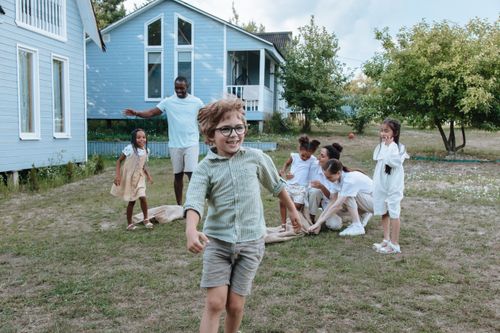 Free Children and adults enjoy a playful time outdoors near blue houses. Stock Photo