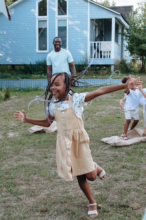 Free Children enjoy a playful day outdoors in a backyard, celebrating joy and togetherness. Stock Photo