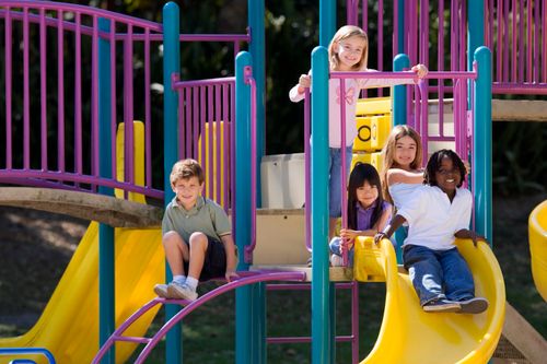 Free A group of diverse children enjoying playground slides on a sunny day outdoors. Stock Photo