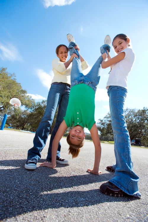 Free Three kids having fun doing handstands outside, smiling and enjoying a sunny day together. Stock Photo