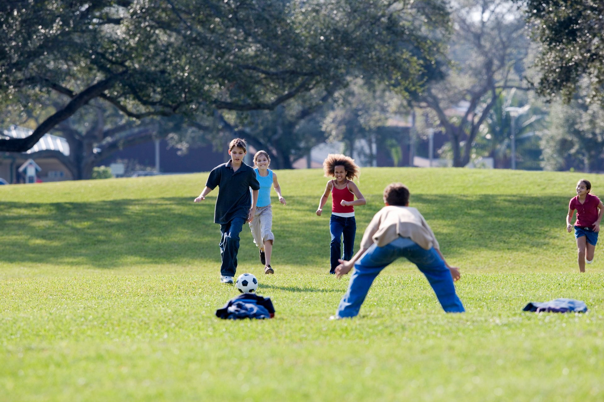 Group of young children playing soccer together on a grass field