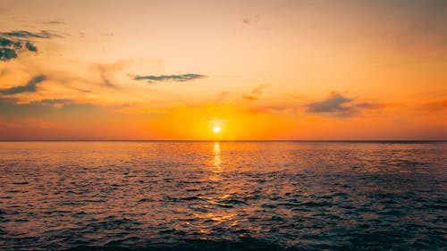 Free  Calm Ocean Under the Orange Sky with Sun Stock Photo