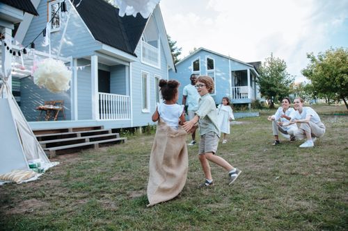 Free Children and adults enjoying a lively sack race in the yard during a family celebration. Stock Photo