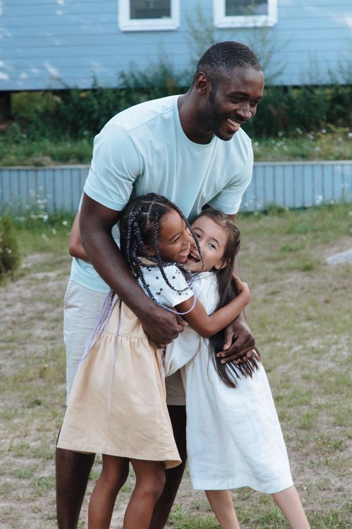 Free A joyful moment with a father embracing his daughters with love and happiness in an outdoor setting. Stock Photo