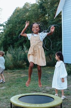 Happy kids enjoy a fun afternoon jumping on a trampoline in a garden.