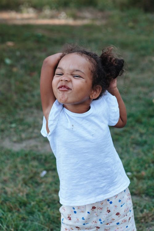 Free A happy young girl with hands behind her head enjoys a sunny day outdoors, smiling brightly. Stock Photo