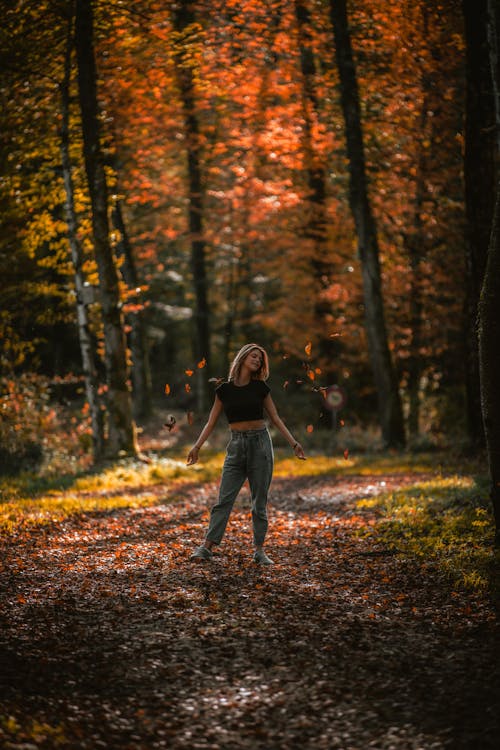 Free Woman Wearing Crop Top Standing on Fallen Leaves Stock Photo