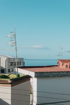 A serene view of building rooftops with antennas against the blue Tyrrhenian Sea in Torre del Greco, Italy.