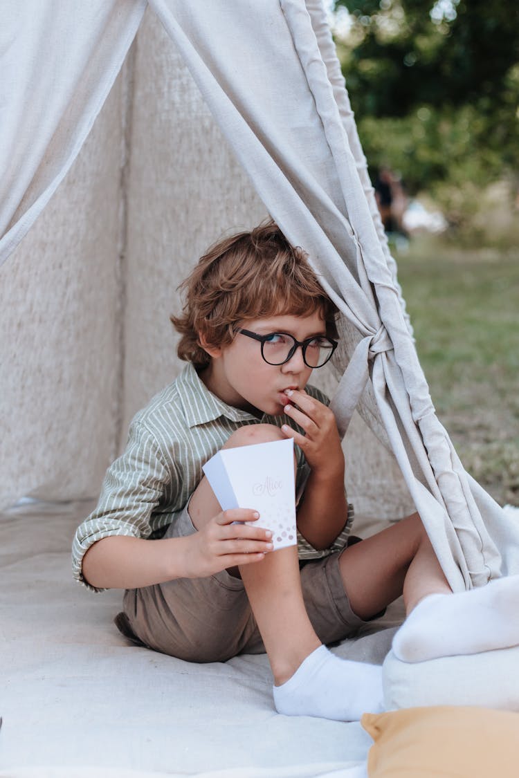 Boy Sitting In Teepee And Eating Popcorn