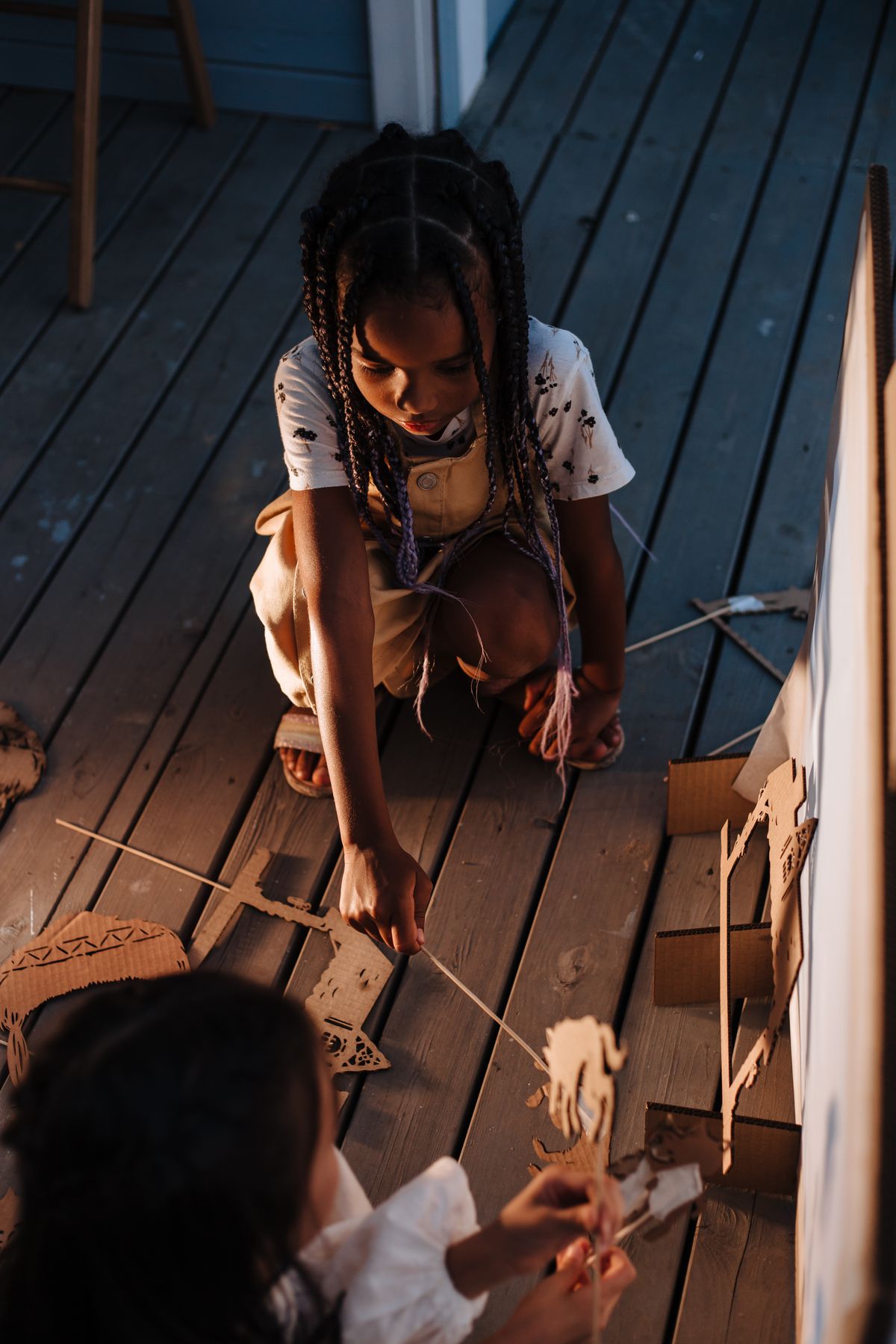 Two children playing with homemade cardboard puppets, ready for a horse puppet show
