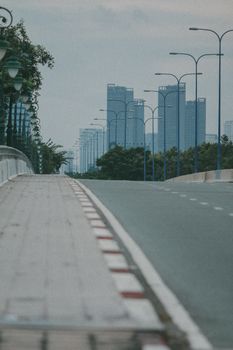 A serene urban scene featuring an empty street and towering skyscrapers under a cloudy sky.