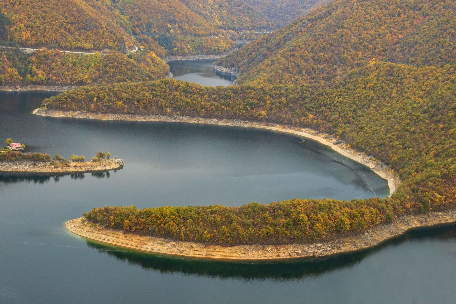 Beautiful aerial view of a river winding through a forest during autumn, showcasing stunning fall colors.