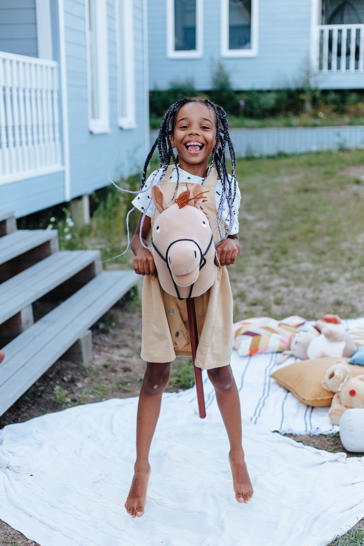 A happy girl playing outdoors with her homemade toy hobby horse