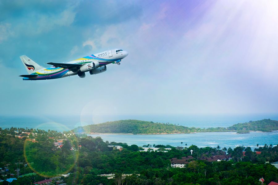 Airplane over tropical island — domestic flights Thailand