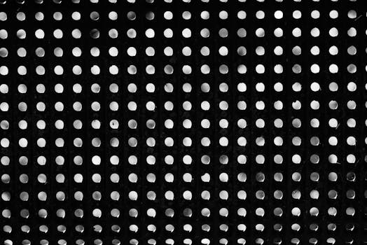 Black and white image featuring a repetitive dotted pattern with circular shapes creating an abstract design.