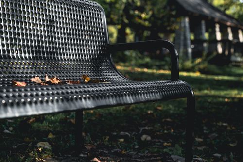 Free A serene metal bench in a park covered with dry leaves, capturing the essence of a fall day. Stock Photo
