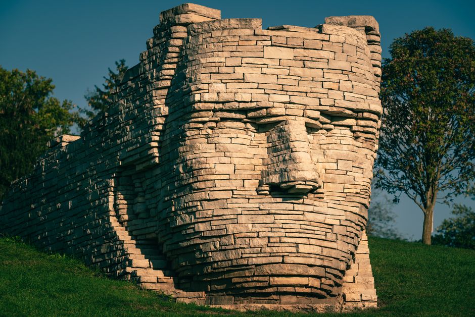 Close-up view of a striking stone face sculpture on a sunny day.