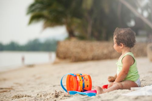 Free A young child plays happily with a bucket and sand on a tropical beach in Thailand. Stock Photo