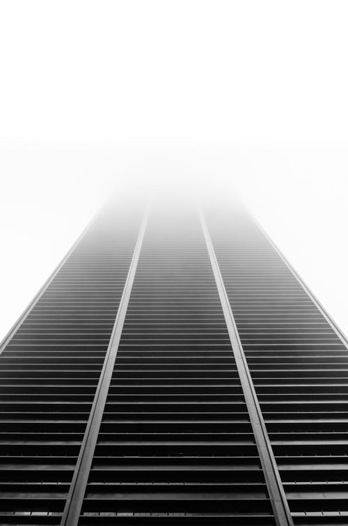 Free A modern high-rise building disappearing into the fog, captured in monochrome for a futuristic feel. Stock Photo