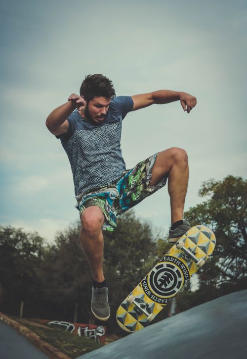 Free Young man performing an impressive skateboarding trick in a vibrant outdoor park. Stock Photo