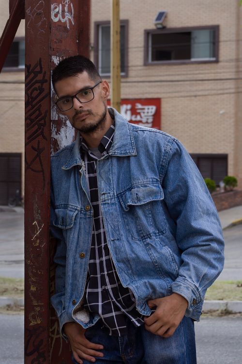 Free Stylish young man wearing denim jacket in a city setting with graffiti. Stock Photo