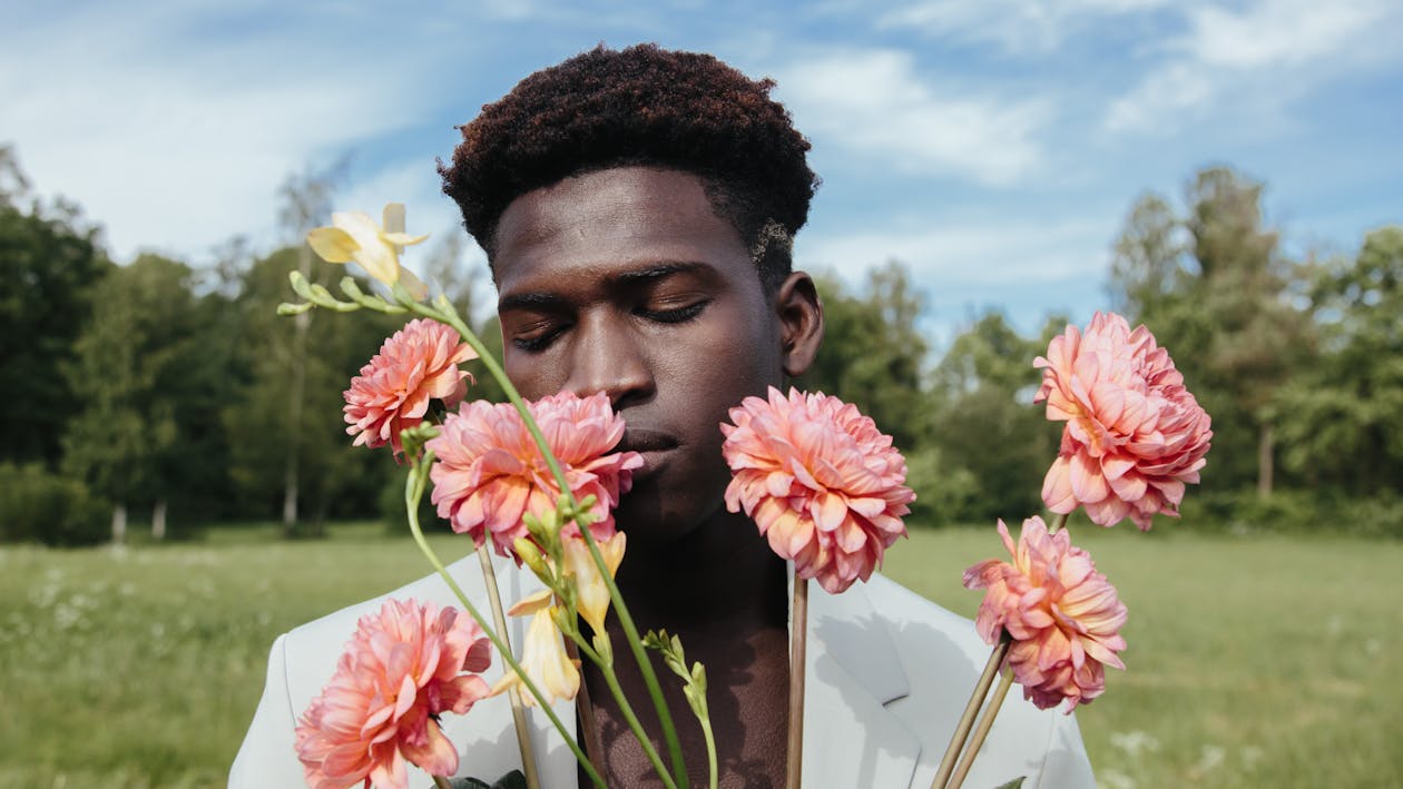 Close-Up Shot of a Man in White Suit Holding Pink Flowers