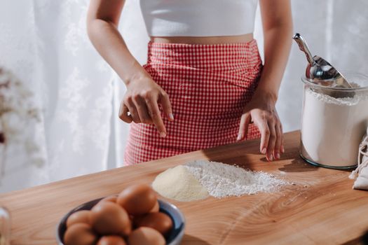 Close-up of a woman preparing fresh pasta with flour on a wooden table.